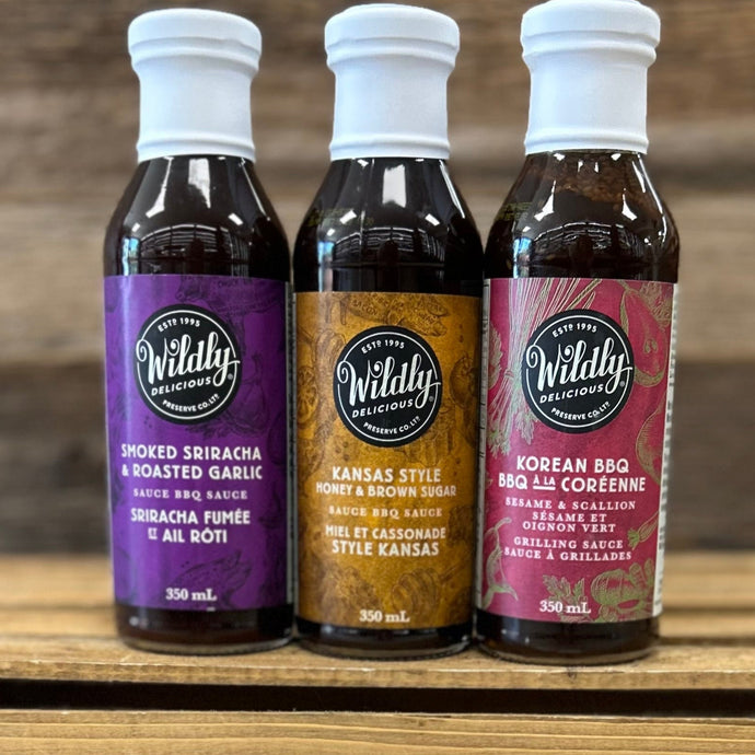 Set of Wildly Delicious BBQ sauce bottles on a wooden crate with a blurred background