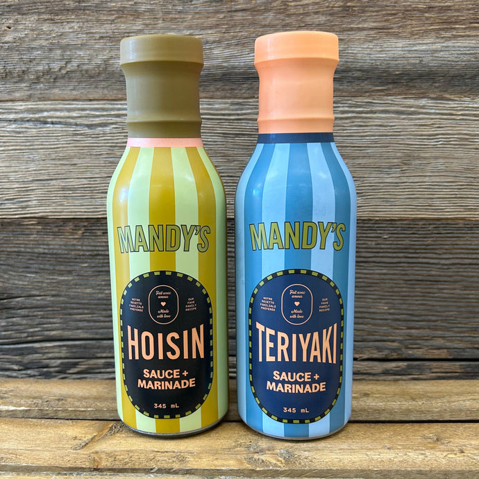 Two bottles of Mandy's sauce on a wooden surface