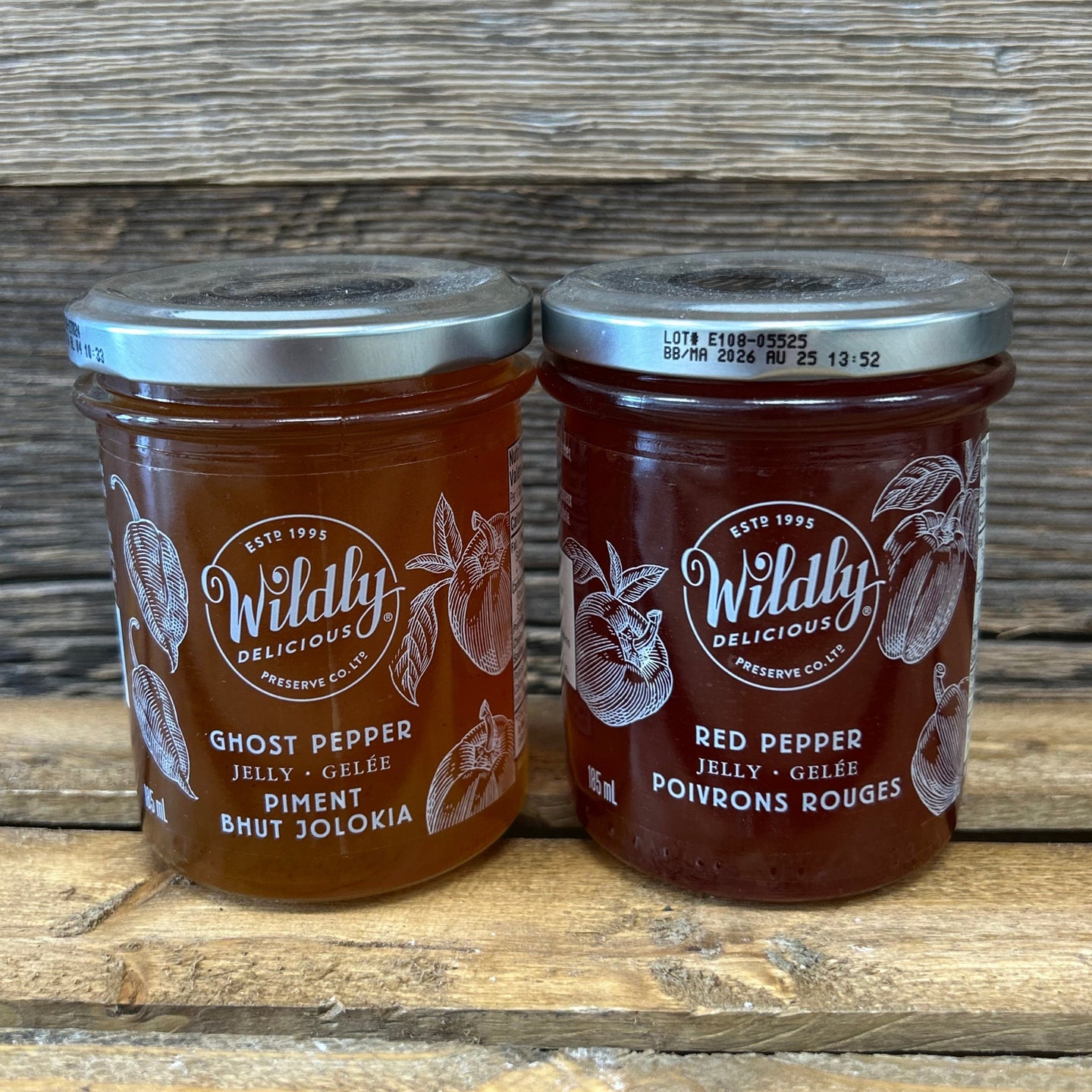 Two jars of Wildly Delicious Red Pepper jelly on a wooden surface