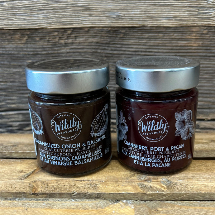 Two jars of Wildly Delicious charcuterie preserves on a wooden surface