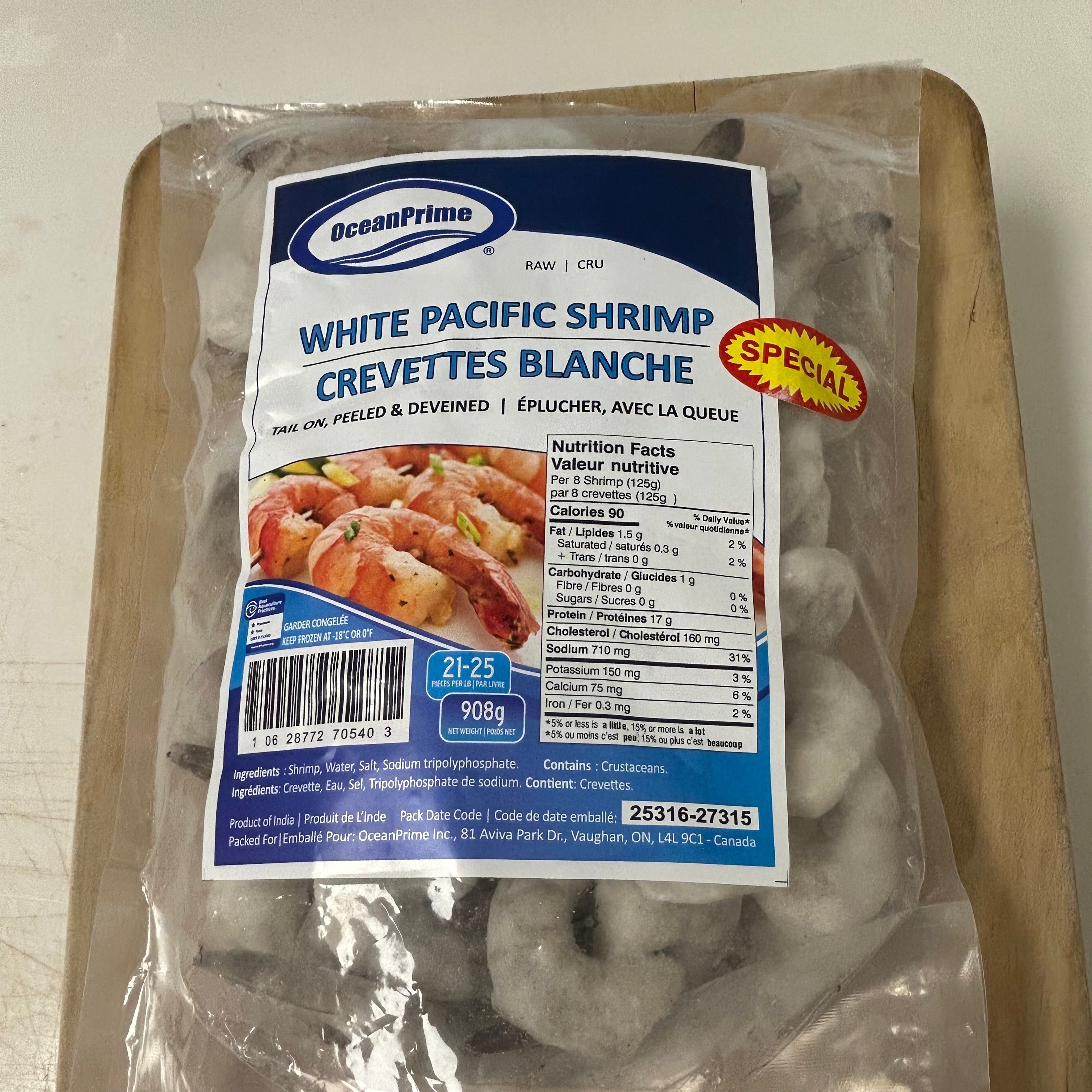 A 500g vacuum-sealed package of OceanPrime White Pacific Shrimp (crevettes blanches) on a wooden cutting board.