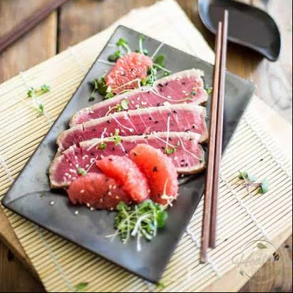 Slices of raw tuna tataki served on a black rectangular plate